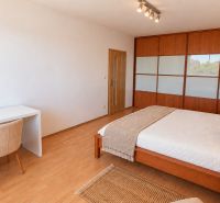 Priestranný 2i byt, loggia, klíma, projekt MONDRIAN, Sedmokrásková ul. - Spálňa v 2-izbovom byte s posteľou, písacím stolom a podlahou s dreveným dekorom.