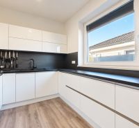 4-izbový dom 96m2 + pozemok 417m2  | Kostolište - Kuchyňa v rodinnom dome s čiernymi spotrebičmi a podlahou s dreveným dekorom.