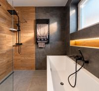 4-izbový dom 96m2 + pozemok 417m2  | Kostolište - Kúpeľňa v rodinnom dome so sprchovacím kútom, vaňou a obkladmi v drevenom dekore.