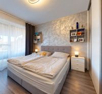 4-izbový dom 96m2 + pozemok 417m2  | Kostolište - Spálňa s mäkkým čelom postele a podlahou s dreveným dekorom v rodinnom dome.