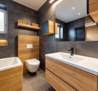4-izbový dom 96m2 + pozemok 417m2  | Kostolište - Kúpeľňa s tmavými obkladmi a podlahou s dreveným dekorom v rodinnom dome.