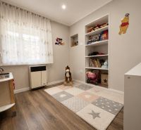 INVESTIČNÁ PRÍLEŽITOSŤ V SRDCI ŠTÚROVA - ZABEHNUTÉ APARTMÁNY - Detská izba v rodinnom dome s hračkami, poličkami a podlahou s dreveným dekorom.