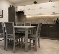 INVESTIČNÁ PRÍLEŽITOSŤ V SRDCI ŠTÚROVA - ZABEHNUTÉ APARTMÁNY - Kuchynský kút v rodinnom dome s jedálenským stolom a kamennou stenou.