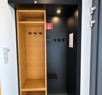 Predaj! INVESTUJTE DO MIESTA, KAM SA ĽUDIA VRACAJÚ – TATRALANDIA - Vstupná časť rodinného domu s dreveným dekorom, úložným priestorom a tmavými stenami.