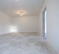 Posledný Voľný - Moderný 4-izbový rodinný dom s terasou a záhradou - Prázdna miestnosť rodinného domu so surovou betónovou podlahou a bielymi stenami.