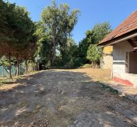 Rodinný dom v centre obce s potokom priamo za domom - Dvor rodinného domu na Námestí sv. Floriána v Krakovanoch obklopený zeleňou a stromami.