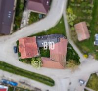 Investičná príležitosť - Dom s bývalou prevádzkou - Letecký pohľad na rodinný dom v Púchove obklopený cestami a zelenými plochami.