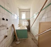 Investičná príležitosť - Dom s bývalou prevádzkou - Kúpeľňa rodinného domu s opotrebovanými kachličkami a vaňou čakajúcou na renováciu.