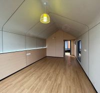 NUERA I PREDAJ - Montovaný domček za pár dní, NATUR HOUSE - Interiér chaty s podlahou s dreveným dekorom a efektným závesným svietidlom.