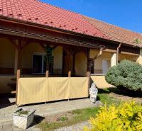 5 IZB. RODINNÝ DOM S ROZĽAHLÝM POZEMKOM 2 751 m² – NADLICE - V Nadliciach rodinný dom so zastrešenou terasou, kríkom a soškou v záhrade.