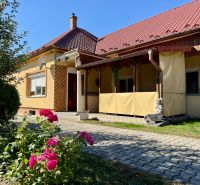 5 IZB. RODINNÝ DOM S ROZĽAHLÝM POZEMKOM 2 751 m² – NADLICE - Rodinný dom v Nadliciach s červenou strechou, záhradou a kvetmi.