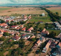 5 IZB. RODINNÝ DOM S ROZĽAHLÝM POZEMKOM 2 751 m² – NADLICE - Letecký pohľad na rodinné domy v obci Nadlice obklopené poľami a kostolom.