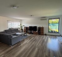 ** NOVOSTAVBA S KRBOM ** 4 izb. RD, ÚP 130m2, pozemok 584m2 – FIGOVÁ - Obývacia izba v rodinnom dome s tmavou sedacou súpravou a podlahou s dreveným dekorom.