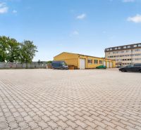 Prenájom 36m2 kancelárie | ul. Brnianska | Trenčín - Parkovisko a žltá budova na Brnianskej ulici v Trenčíne, vhodné pre kancelárie.