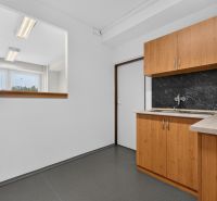 Prenájom 39m2 kancelárie | ul. Brnianska | Trenčín - Kancelárie so sivou podlahou, dreveným dekorom skriniek a oknom pre prirodzené svetlo.