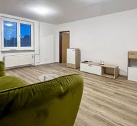 2-izbový byt 80m2 | Bratislavská - Svätý Jur - Obývačka v 2-izbovom byte s podlahou s dreveným dekorom, zelenou pohovkou a moderným nábytkom.