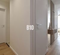 Rezervované-BÔRIK - 4-izbový BYT S GARÁŽOU - Interiér 4-izbového bytu s podlahou s dreveným dekorom a minimalistickým nábytkom.