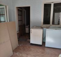 Predám 3 izbový dom v Tvrdošovciach - Izba v rodinnom dome s podlahou s dreveným dekorom a starším nábytkom.