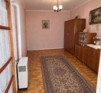 Predám 3 izbový dom v Tvrdošovciach - Interiér rodinného domu s podlahou s dreveným dekorom, kobercom a skrinkami.