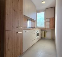 Moderne vybavený a zariadený 1-izbový byt s balkónom na sídlisku JUH - Kuchyňa v 1-izbovom byte s dreveným dekorom a vstavanými spotrebičmi.