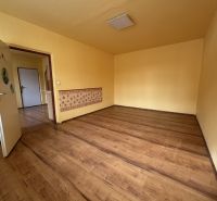 PREDAJ: 1 izbový byt; 38 m²; BREZNO ;89.500 € - Izba s podlahou s dreveným dekorom v 1-izbovom byte so žltými stenami.