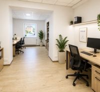 Na prenájom obchodný priestor v centre Pezinka 100m2 - Obchodné priestory so stolmi, kancelárskymi stoličkami a podlahou s dreveným dekorom.