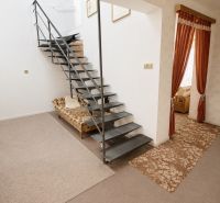 Priestranný 5izbový RD v Dolných Orešanoch 733m2 - Interiér rodinného domu s oceľovým schodiskom, kobercom a závesmi.