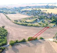 Podhájska - 2.084 m2 POZEMOK na okraji obce - Poľnohospodárske a lesné pozemky v Podhájskej, okolité polia a vzdialené budovy.