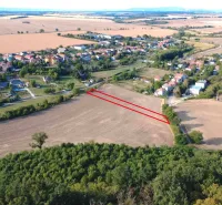 Podhájska - 2.084 m2 POZEMOK na okraji obce - Letecký pohľad na poľnohospodárske a lesné pozemky v Podhájskej, s dedinou v pozadí.