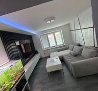 Ponúkame moderne zariadený byt na Zelenečskej  - Obývačka 2-izbového bytu s podlahou s dreveným dekorom, sedačkou a akváriom.