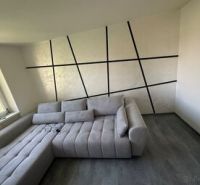 Ponúkame moderne zariadený byt na Zelenečskej - Interiér 2-izbového bytu s pohodlnou sedačkou a podlahou s dreveným dekorom.