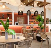 Hotelový a rezidenčný komplex THE TERRACE v Paje, Zanzibar - Interiér s dreveným dekorom, prútenými stoličkami a rastlinami v rámci výstavby bytov.