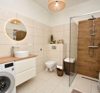  Predaj zrekonštruovanej garsónky v centre mesta Mosonmagyaróvár - Kúpeľňa s práčkou, sprchovacím kútom a podlahou s dreveným dekorom v 1-izbovom byte.