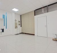 Priestor pre vaše podnikanie na prenájom v Šali – Veča - Interiér obchodných priestorov s kreslom, zrkadlami a dlažbou s bielym vzorom.