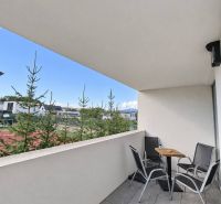ViBee Liptov:apartmán s odhadom 5 % hrubého výnosu a vlastnými pobytmi - Balkón 2-izbového bytu s posedením, výhľadom na zeleň a modernou dlažbou.