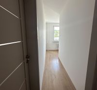 2-izb. byt, Galbavého, Dúbravka, kompletná rekonštrukcia  - Chodba s bielymi stenami a podlahou s dreveným dekorom v 2-izbovom byte.