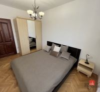 Priestranný 3i byt s balkónom a garážou v Petržalke - Spálňa v 3-izbovom byte s manželskou posteľou a skriňou, podlaha s dreveným dekorom.