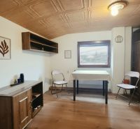 Na predaj zabehnutý Apartmánový dom v Podhájskej s parkovaním - Interiér Rekreačného apartmánu s nábytkom z dreveným dekorom a skladacími stoličkami.