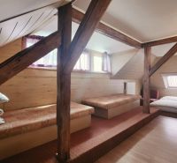 Na predaj zabehnutý Apartmánový dom v Podhájskej s parkovaním - Podkrovná izba v rekreačnom apartmáne s podlahou s dreveným dekorom a lôžkami.