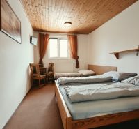 Na predaj zabehnutý Apartmánový dom v Podhájskej s parkovaním - Spálňa v Rekreačnom apartmáne s dvomi posteľami a TV, podlaha s dreveným dekorom.