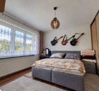 Zrekonštruovaný rodinný dom 215 m² na pozemku 1 530 m² | Martin - Spálňa v rodinnom dome s gitarami na stene, podlaha s dreveným dekorom.