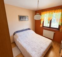 Rodinný dom s garážou a veľkorysou dispozíciou | SL - Spálňa v rodinnom dome s posteľou, závesmi a podlahou s dreveným dekorom.
