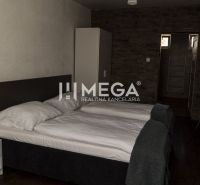 Na predaj nehnuteľnosť - zabehnutý penzión v centre mesta Humenné - Izba s dvomi posteľami, stolíkom a podlahou s dreveným dekorom. Hotely a penzióny.