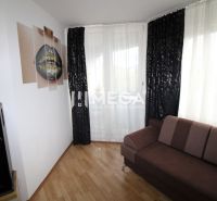 REZERVOVANÝ - Na predaj moderný 2-izbový byt po rekonštrukcii - Obývacia izba v 2-izbovom byte s tmavou pohovkou, reproduktorom a podlahou s dreveným dekorom.