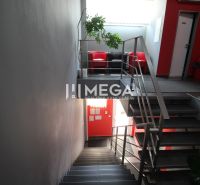 NA PRENÁJOM: 2x Moderná, klimatizovaná kancelária s parkovaním a optic - Chodba v kanceláriách s kovovým zábradlím a červeným kreslom.