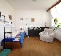 DOHODA NA CENE NA PREDAJ 4-IZBOVÝ BYT 88 m² S LOGGIOU HUMENNÉ - Izba v 4-izbovom byte s posteľou, kreslom a podlahou s dreveným dekorom.