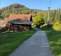 Stavebný pozemok 750 m2 v Košeckom Podhradí - Cesta v Košeckom Podhradí vedie popri domoch, lemovaná zeleňou a kopcami. Pozemky - bývanie.