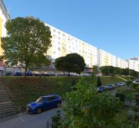 Praktický 3i BYT s obľúbenou dispozíciou - Rozkvet - PB - Sídlisko Rozkvet v Považskej Bystrici s bytovými domami a zaparkovanými autami.