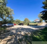 8,5 árov pokoja a krásnych výhľadov na okraji intravilánu - Auta parkujú na spevnenej ploche pri záhradách v Pastuchove pod jasnou modrou oblohou.