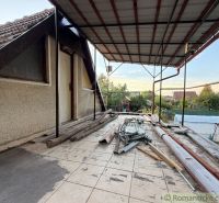 Záhrada s murovanou chatkou po rekonštrukcii iba 200 m od rieky Nitra - Terasa chaty v Nových Zámkoch s neporiadkom a stavebným materiálom, pokojná záhrada v pozadí.